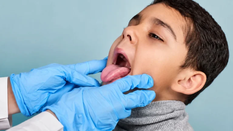 Child undergoing ENT throat examination for understanding when to remove adenoids in child in a modern pediatric clinic setting.